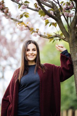 Bahar çiçekli. Genç kadının yanına pembe çiçekli sakura ağacı açık havada