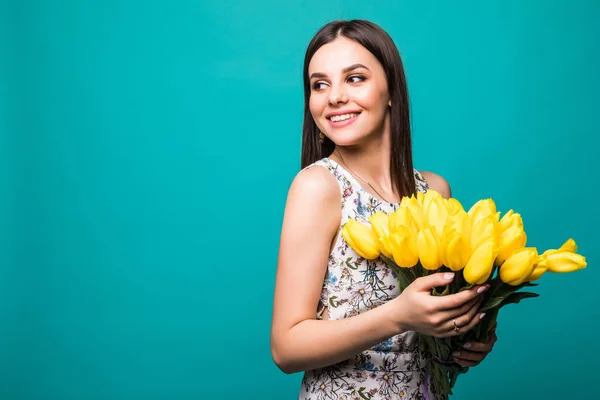 Ritratto di giovane donna sorridente con bouquet di tulipani gialli isolato su sfondo blu — Foto Stock