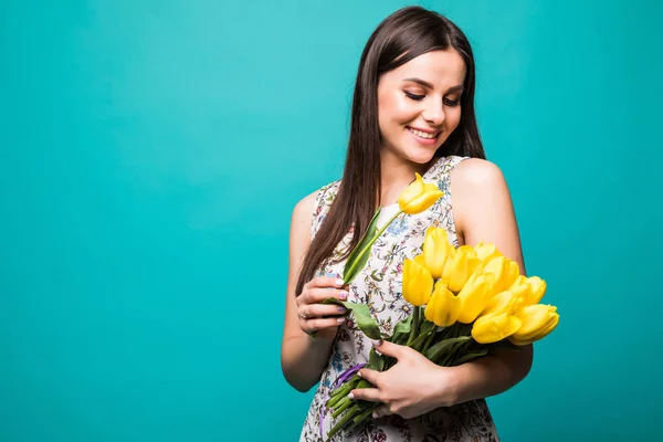 Cadeau d'anniversaire. Belle fille dans la robe comptant les fleurs tulipes dans les mains sur un fond bleu — Photo