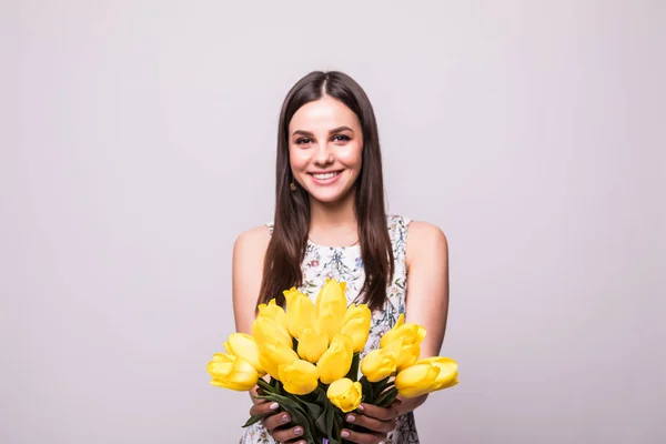 Fiatal nő virágok sárga tulipánok, kezében a világos háttér-portré — Stock Fotó