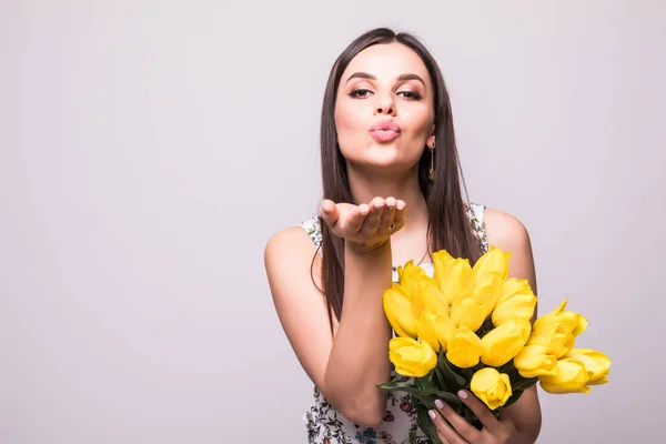 Ti mando i miei migliori auguri. Felice giovane donna colpo bacio con tulipani gialli isolato su sfondo bianco — Foto Stock