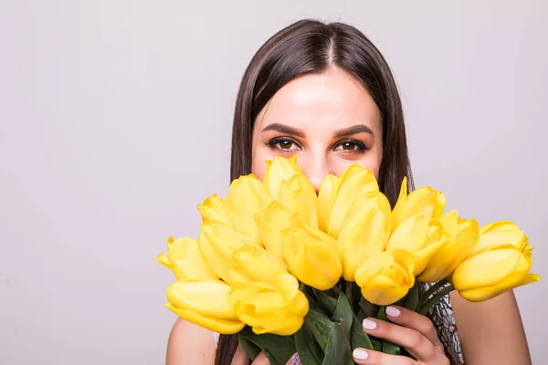 Regalo di fiori. Bella donna felice nel vestito con fiori tulipani in mano su uno sfondo bianco — Foto Stock