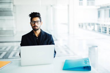 Zor ofis işleri. Ofiste çalışan genç yakışıklı Hintli erkek