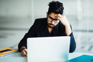 Modern ofis masasında oturan elinde kafa ile sinirli işadamı