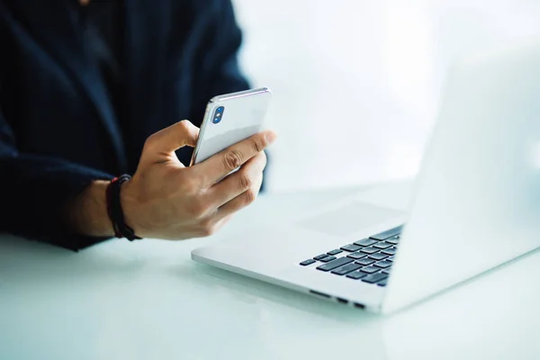 Närbild av affärsman med mobiltelefon och bärbar dator på skrivbord i moderna kontor — Stockfoto