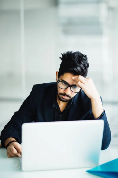Zdjęcie z Indian Mężczyzna niezadowolony z pracy, siedząc na laptopa w nowoczesnym biurze — Zdjęcie stockowe