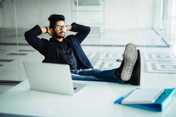 Jeune homme d'affaires indien travaillant dans son bureau avec les pieds sur le bureau — Photo