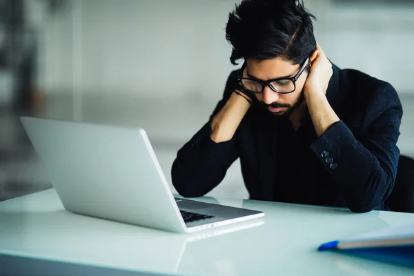 Müder und besorgter indischer Geschäftsmann am Arbeitsplatz im Büro mit händendem Kopf — Stockfoto