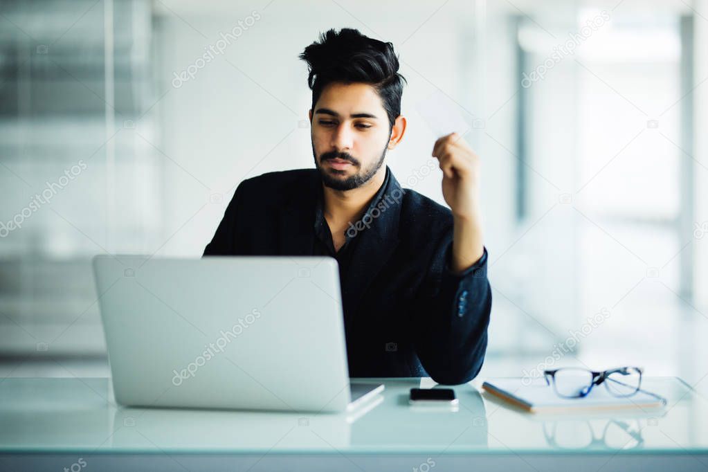 Concetrated indian man smiling and working at office