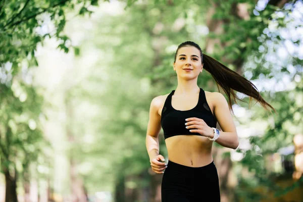 Junge lächelnde, sportliche Frau beim Laufen im Park. Fitness-Mädchen joggt im Park — Stockfoto