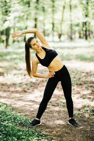 Retrato de uma jovem saudável fazendo exercício de alongamento no parque — Fotografia de Stock
