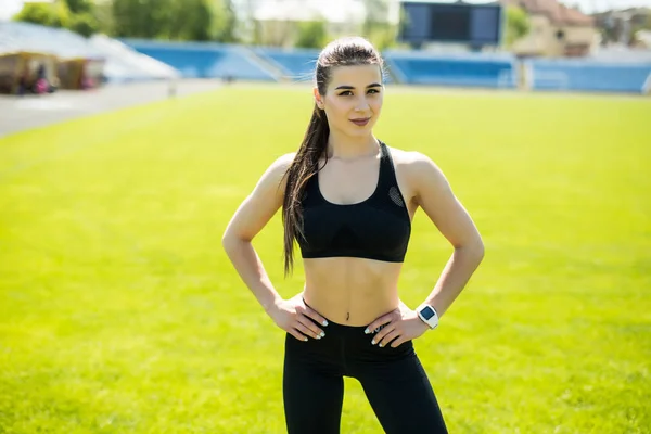 Onun yaşam spor. Gülümseyen spor kadın kolları ile ayakta stadyum üzerinde katlanmış — Stok fotoğraf