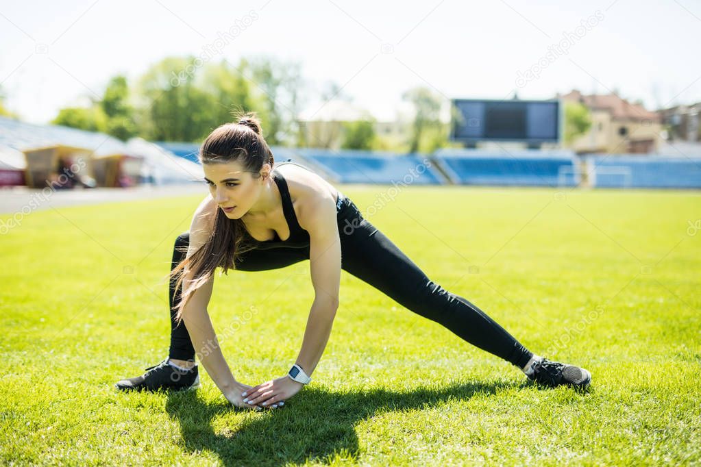 beautiful sports girl is engaged in a sports stadium. Warming up the muscles before training.
