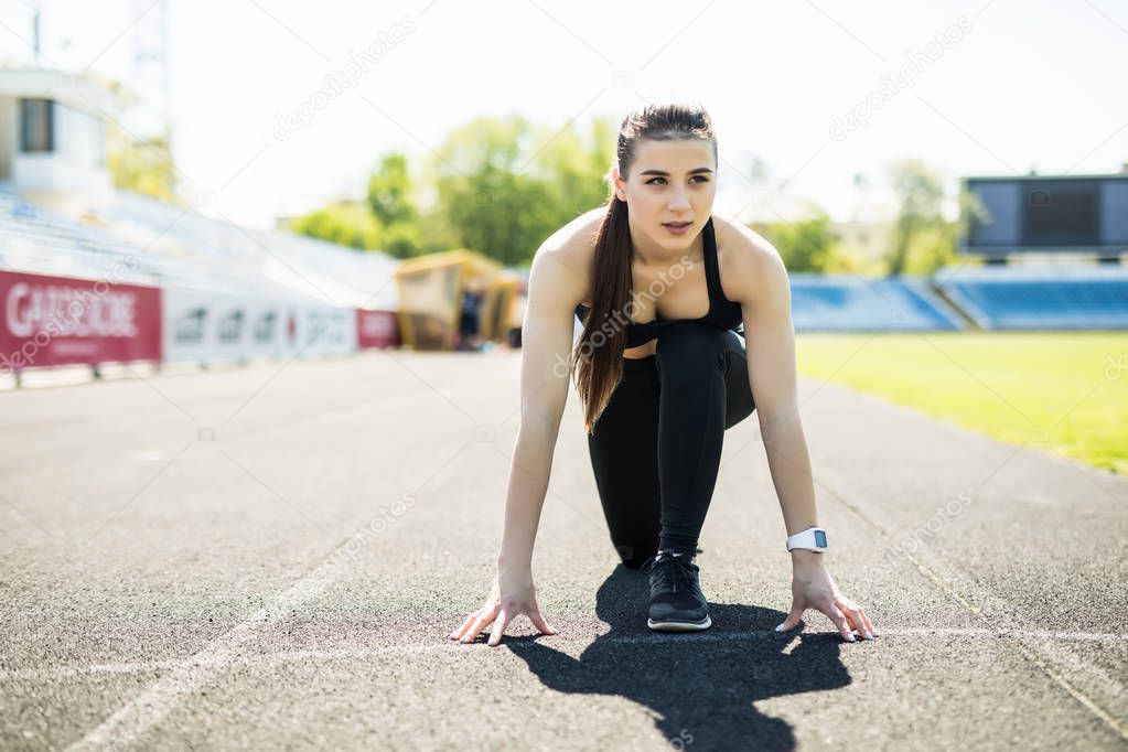 Fitness athlete on starting near stadium track preparing for a sprint. Fitness, healthy lifestyle concept