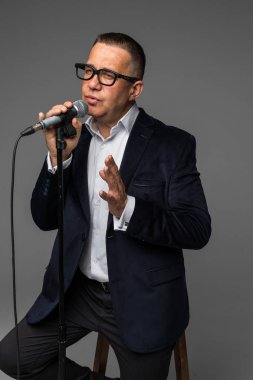 Bir mikrofon ile bir şarkı söylerken, bir olayın başvuran veya bir parti adamı mutlu ve motive, orta yaşlı, izole anın tadını çıkarın