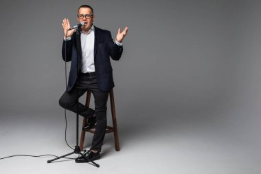 Beyaz arka plan üzerinde izole bir mikrofon tutan kıdemli mutlu bir adam