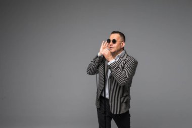 Orta yaş şovmen görüşmeci duygularla. Beyaz arka plan üzerinde mikrofon tutan genç zarif olgun adam. Şovmen kavramı.