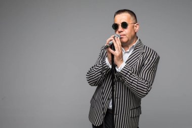 Orta yaş şovmen görüşmeci duygularla. Beyaz arka plan üzerinde mikrofon tutan genç zarif olgun adam. Şovmen kavramı.