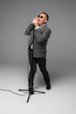 Orta yaş şovmen görüşmeci duygularla. Beyaz arka plan üzerinde mikrofon tutan genç zarif olgun adam. Şovmen kavramı.