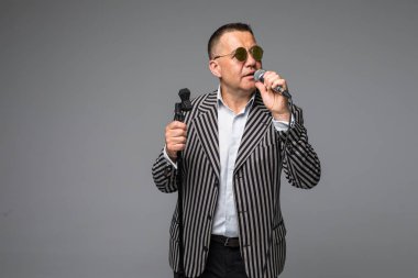 Orta yaş erkek takım elbise şarkı üzerinde mikrofon enerji ile. Beyaz arka plan üzerinde izole. Şarkıcı kavramı.