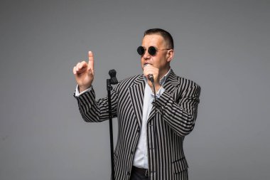 Orta yaş erkek takım elbise şarkı üzerinde mikrofon enerji ile. Beyaz arka plan üzerinde izole. Şarkıcı kavramı.