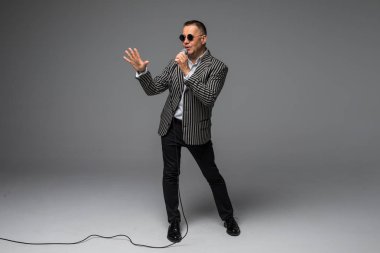 Orta yaş şovmen görüşmeci duygularla. Beyaz arka plan üzerinde mikrofon tutan genç zarif olgun adam. Şovmen kavramı.