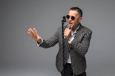 Orta yaş erkek takım elbise şarkı üzerinde mikrofon enerji ile. Beyaz arka plan üzerinde izole. Şarkıcı kavramı.