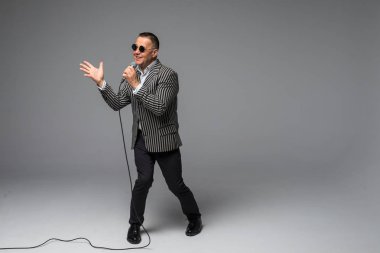 Orta yaş şovmen görüşmeci duygularla. Beyaz arka plan üzerinde mikrofon tutan genç zarif olgun adam. Şovmen kavramı.