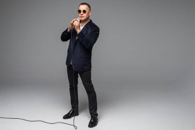 Orta yaş şovmen görüşmeci duygularla. Beyaz arka plan üzerinde mikrofon tutan genç zarif olgun adam. Şovmen kavramı.