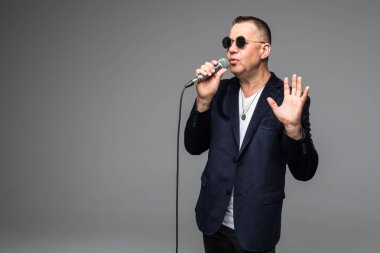 Orta yaş şovmen görüşmeci duygularla. Beyaz arka plan üzerinde mikrofon tutan genç zarif olgun adam. Şovmen kavramı.