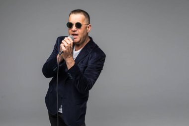 Orta yaş şovmen görüşmeci duygularla. Beyaz arka plan üzerinde mikrofon tutan genç zarif olgun adam. Şovmen kavramı.