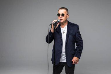 Orta yaş şovmen görüşmeci duygularla. Beyaz arka plan üzerinde mikrofon tutan genç zarif olgun adam. Şovmen kavramı.