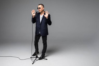 Orta yaş şovmen görüşmeci duygularla. Beyaz arka plan üzerinde mikrofon tutan genç zarif olgun adam. Şovmen kavramı.