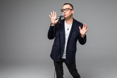 Orta yaş şovmen görüşmeci duygularla. Beyaz arka plan üzerinde mikrofon tutan genç zarif olgun adam. Şovmen kavramı.