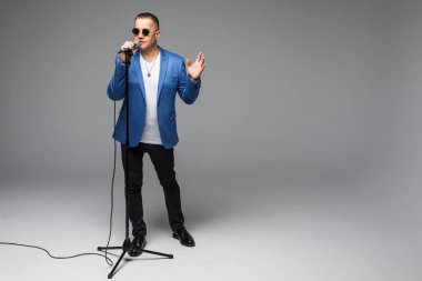 Orta yaş şovmen görüşmeci duygularla. Beyaz arka plan üzerinde mikrofon tutan genç zarif olgun adam. Şovmen kavramı.