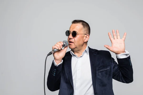 Portræt af en senior mand synger i mikrofon isoleret på hvid baggrund - Stock-foto
