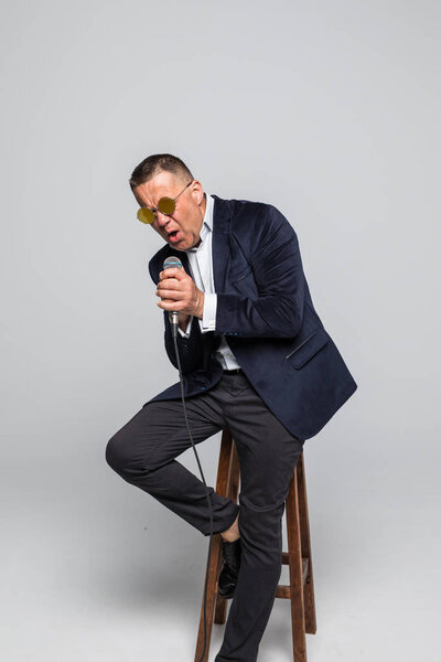 портрет пожилого человека, поющего в микрофон на белом фоне
