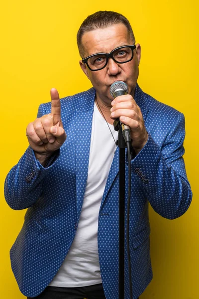 Portrait of mature man singing on yellow background — Stock Photo, Image