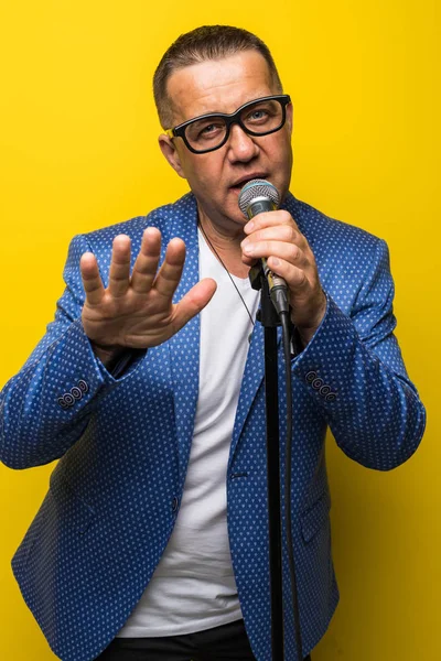 Portrait of mature man singing on yellow background — Stock Photo, Image