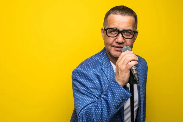 Portrait of mature man singing on yellow background — Stock Photo, Image