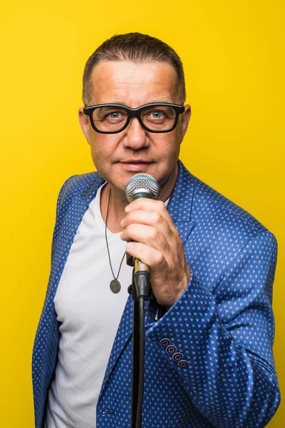 Portrait of mature man singing on yellow background — Stock Photo, Image