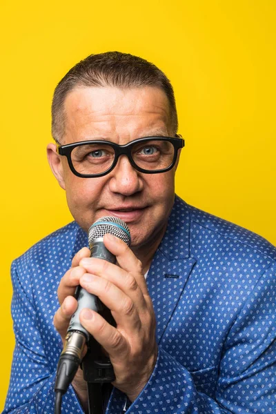 Portræt af moden mand synger på gul baggrund - Stock-foto