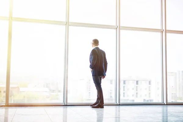 Homme d'affaires senior regardant par la fenêtre panoramique dans le bureau — Photo