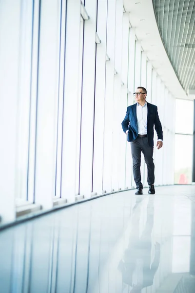 Image pleine longueur d'un homme d'affaires d'âge moyen marchant vers la caméra et souriant dans un immeuble de bureaux — Photo