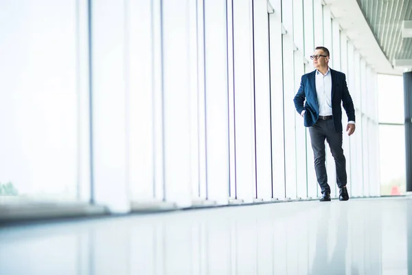 Красивый и успешный старший бизнесмен, прогуливающийся по современному офисному интерьеру — стоковое фото