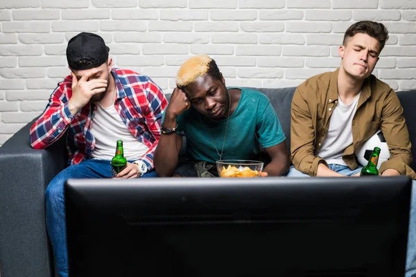Los amigos molestos ven un fútbol con cerveza y snaks tristes de perder de su equipo sentado en el sofá —  Fotos de Stock