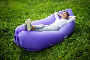 Bir ara verelim. Genç ve güzel kadın güneş Park'ta çimenlerin üzerinde dinlenme sırasında şişme kanepe lamzac yalan