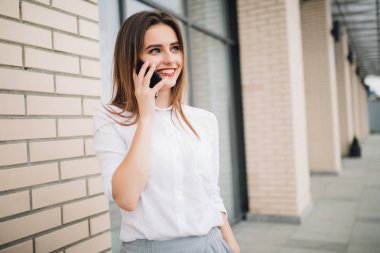 Şehrin telefondaki mutlu kadın. Gülümseyen kadın cep telefonu bina önünde söz.