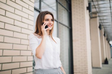 Şehrin telefondaki mutlu kadın. Gülümseyen kadın cep telefonu bina önünde söz.