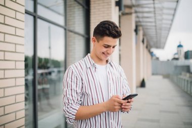 Adam manifatura telefon. Mutlu dış ofis binası gülümseyen smartphone kullanarak rahat kentsel profesyonel girişimci. Açık sokakta mobile ile modern genç adam portresi